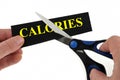 Diet concept with someone cutting the word calories with scissors on white background