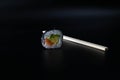 Close-up of a piece of philadelphia sushi with chopsticks