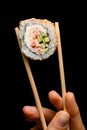 Close-up of piece of roll california with snow crab meat, cream cheese, cucumber garnished sesame seeds in bamboo