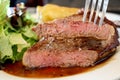 Close-up piece sliced in the fork of sirloin beef steak with brown sauce in white plate background. Medium level ripe. Foods