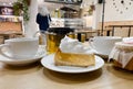 Close-up of piece transparent gelatin cake with meringue cream on table in cafe with blurred visitor