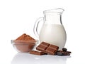 Close-up pieces of chocolate bar with cocoa beans, bowl of cocoa powder and glass jug of milk