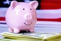 Close up piggy bank and money in front of US flag as symbol of economy of the United States of America
