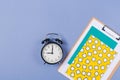 Close up of Pile of bright notebooks, clipboard, alarm- clock and stationary on blue desk top. Copy space. Free space