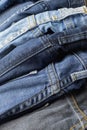 Close up of pile of casual black and blue jeans with seam and thread detail. Vertical full frame background Royalty Free Stock Photo