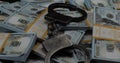 Close-up of a pile of hundred dollar bills with handcuffs on a black background. Dollars with handcuffs lying on them