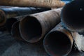 Close up of a pile of large and rusting steel pipes lying