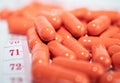 close-up of a pile of orange pills and approach of the number 71 of a white tape measure. Royalty Free Stock Photo