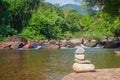 Close up pile of pebbles with beautiful landscape view of small waterfall in the river with water stream flowing through stone. Royalty Free Stock Photo