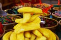 Close up of pile of sweets in shape of yellow banana with blurred bowels filled with sweet candies background on French market