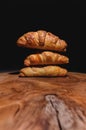 Close-up of a pile of three croissants on a wooden board against a dark background. Delicious and healthy breakfast