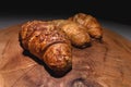 Close-up of a pile of three croissants on a wooden board against a dark background. Delicious and healthy breakfast