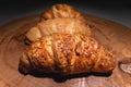 Close-up of a pile of three croissants on a wooden board against a dark background. Delicious and healthy breakfast