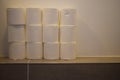 A close up of a pile of toilet paper rolls stacked in a bathroom. Toilet paper panic buying and hoarding