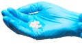 Close up of pile of white heart shape tablets on female doctor's hand in blue sterilized surgical glove