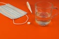 Close-up Of A Pill, Thermomicrometer, Medical Mask, Glass Of Water On A Bright Orange Background. Copyspace At The Bottom Of The P