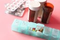 Close up of pills, container and pill box on pink background