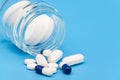 Close up of Pills spilling out of pill bottle on blue background. with copy space. Medicine concept. Royalty Free Stock Photo