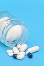 Close up of Pills spilling out of pill bottle on blue background. with copy space. Medicine concept. Royalty Free Stock Photo