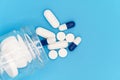 Close up of Pills spilling out of pill bottle on blue background. with copy space. Medicine concept. Top view. Royalty Free Stock Photo