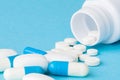 Close up pills spilling out of pill bottle on blue background. Medicine, medical insurance or pharmacy concept