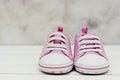 Close up pink baby girl sneakers, sport shoes close up on gray background. Newbord, motherhood, pregnancy concept with copy space