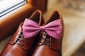 Close-up of a pink bow tie on brown mens shoes.