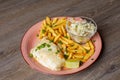 Close-up of plate with French fries, omelette, piece of lime, cabbage salad in small glass bowl sprinkled with greens.