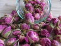 Close up of pink dried rose buds Herbal Tea in glass bottle on wooden background