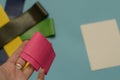 Close up pink elastic expander in hand above colorful set of gum fitness bands and white sheet of paper on blue background.