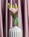 Close up of pink eustoma flowers in a ceramic vase on textile background. Flowers composition, interior decoration..