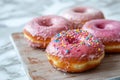 A close-up of pink-frosted donuts with colorful sprinkles on a cooling rack. Perfect for celebrating National Donut Day