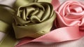 a close up of a pink and a green satin flower on a white sheet with a pink satin ribbon on the end of the flower