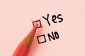Close-up of pink pencil and yes no checkbox with yes box checked - Concept of women issues and Yes or No choice