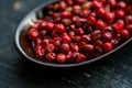 Close up pink peppercorn in spoon dark background