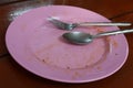 Close-up of pink plastic plates and utensils that have been eaten on the dining table. Royalty Free Stock Photo