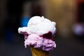 Close up of of pink, purple and white scoops of ice cream in waffle cone against blurred background