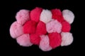 Close up of pink and red rabbit fur pompoms isolated on black background. Top view Royalty Free Stock Photo