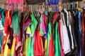 Close-up of pink, red yellow orange, purple, pink, and many designs men and women modern dresses hanging on wood rod in market for Royalty Free Stock Photo