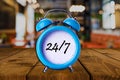 24/7 text on Alarm Clock on wooden table. Royalty Free Stock Photo