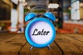 Later text on Alarm Clock on wooden table. Royalty Free Stock Photo