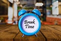 Break time text on Alarm Clock on wooden table.