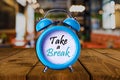 Time for a break text on Alarm Clock on wooden table.