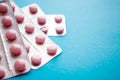 Close up pink tablets in silver blister pack on blue background