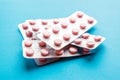 Close up pink tablets in silver blister pack on blue background