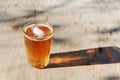 Close up on a pint glass of amber Pale Ale beer, casting a shadow on a old wood table, and space for text