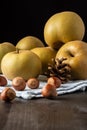 Close-up of pippin apples on blue cloth with hazelnuts, on wooden table, black background,