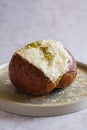 Close-up of a Pistachio Maritozzo on a plate, an italian roman breakfast sweet, whipped cream sandwiched between brioche