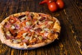 Close up of pizza with ham, tomatoes, sausages and sauce, near a Royalty Free Stock Photo