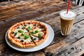 Close-up of a pizza served in a white ceramic plate and cold coffee Royalty Free Stock Photo